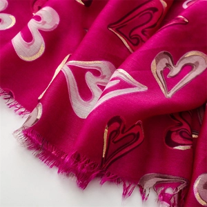 Détail de l'écharpe rouge rose avec cœurs dorés et bords à franges délicates