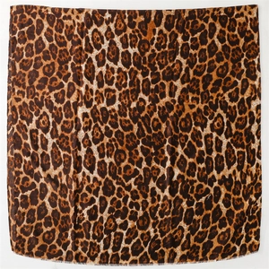Detailed flat lay of a large leopard print scarf with soft frayed edges and silk-like texture