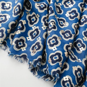 Close-up of blue cotton linen scarf featuring gold foil flower patterns and fringe trim
