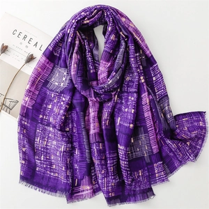 Detail of purple plaid scarf with gold stamped spiderweb patterns and soft fringe edges