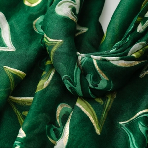 Détail d'une écharpe vert foncé avec motif de cœur doré et texture de tissage