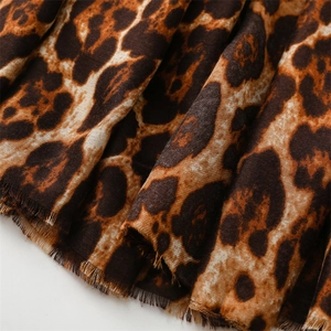 Macro detail of classic leopard print scarf fabric featuring delicate frayed edges