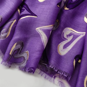 Détail d'une écharpe violette avec motifs de cœurs dorés et bords à franges douces