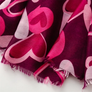 Détail macro d'une écharpe avec motifs de cœurs et bords à franges délicates