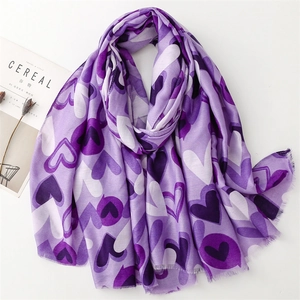Détail d'une écharpe violette à motif cœur avec bords effilochés et magazine Cereal