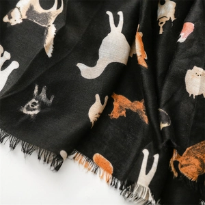 Detailed close-up of cute cartoon dog illustrations on a black cotton linen scarf with tassels