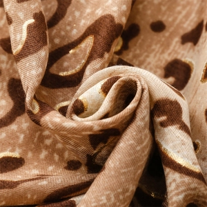 Macro shot of gold foil leopard print on soft linen-feel fabric with shimmering metallic details