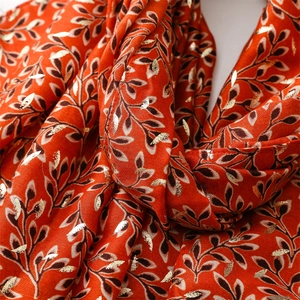 Detail of bright orange scarf with gold foil leaf patterns and soft cotton-linen texture