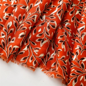 Detail of orange linen scarf with gold foil vine print and soft fringed edges