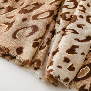 Detail of leopard print scarf with gold foil accents and fringe edges on cotton linen fabric