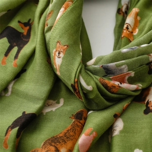 Detail of soft green scarf featuring vivid cartoon dog illustrations and linen texture