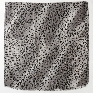 Close-up of leopard print scarf with gold accents and fine fringe edge detail