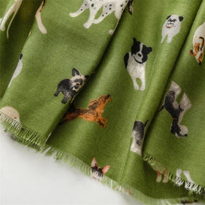 Close-up of green cotton-linen scarf with colorful cartoon dog patterns and frayed edges