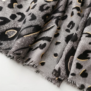 Detail of leopard print scarf with gold foil accents and natural fringed edges