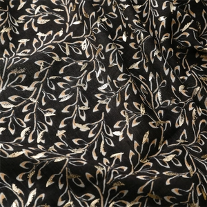 Macro detail of black cotton linen scarf featuring metallic gold leaf foil patterns