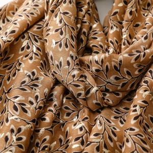 Macro view of gold foil plant patterns on a warm caramel cotton linen scarf