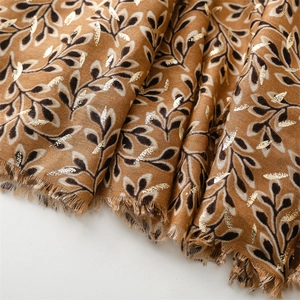Detailed macro view of the gold foil leaf pattern on a brown cotton linen autumn scarf
