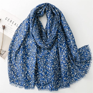 Blue cotton linen scarf with gold leaf print and frayed edges displayed with magazine