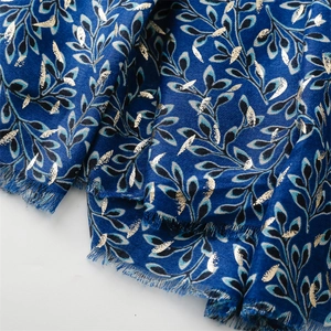 Close-up of navy scarf with metallic gold leaf pattern and frayed fringe edges