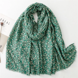 Detail of dark green cotton linen scarf with golden leaf patterns and frayed edges