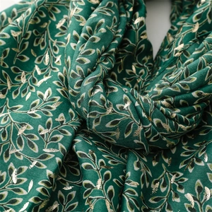 Detail of dark green cotton linen scarf with gold foil vine leaf print and soft texture