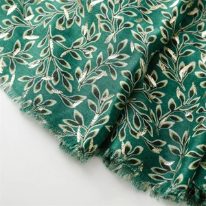 Detail of dark green scarf showing metallic gold leaf print and soft linen-feel texture