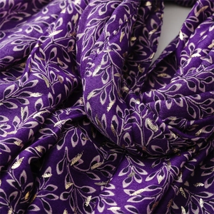 Macro detail of purple fabric with gold foil leaf patterns and soft draped texture
