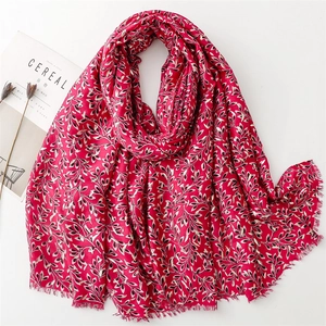 Detail of red oversized scarf featuring gold vine leaf prints and soft fringe edges
