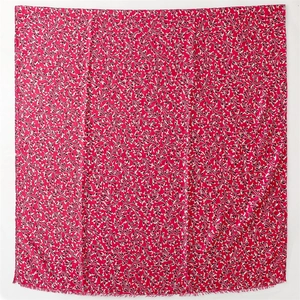 Detail of red scarf showing intricate leaf print pattern and soft fringed edges