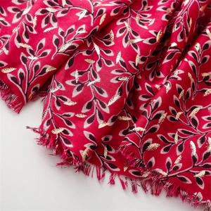 Close-up of red cotton-linen scarf with golden leaf patterns and frayed edges