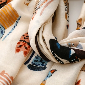 Macro shot showing woven texture and cartoon cat patterns on a beige cotton scarf