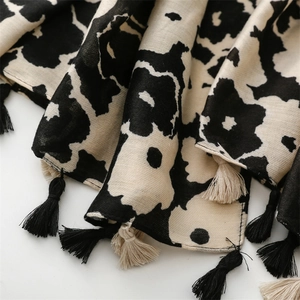 Detail of bohemian cotton-linen scarf with black floral prints and bicolor tassels