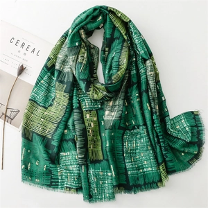 Linen feel scarf with golden web pattern and green geometric design with fringe