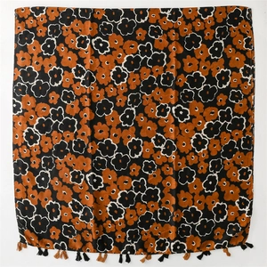 Detail of floral cotton linen scarf featuring black orange blossoms and fringe tassels
