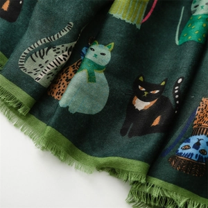 Detailed macro view of dark green scarf featuring cute cat patterns and tassel fringes
