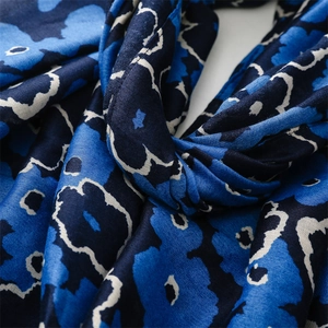 Detailed view of large blue floral print on silky navy scarf with textured folds
