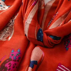 Close-up of vibrant orange cotton-linen scarf featuring cute cartoon cat prints and weave texture