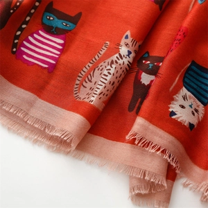 Detail of orange cotton-linen scarf with colorful cartoon cat prints and fringe edges