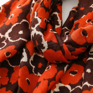 Detail of vintage floral print scarf featuring bold red and brown patterns with soft texture