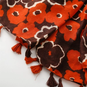 Macro detail of poppy floral print fabric with decorative tassels on thick winter scarf