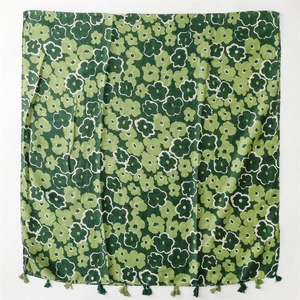Detail of green floral print scarf featuring dense tassel fringe and vintage pattern