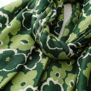 Close-up of green floral poppy pattern on breathable linen-feel fabric scarf