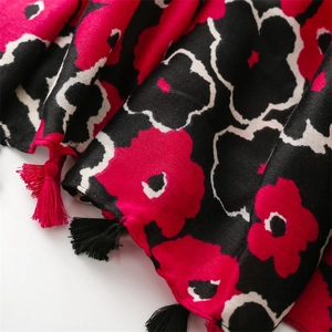 Detail of red floral print on linen scarf with black and red tassels at the edges