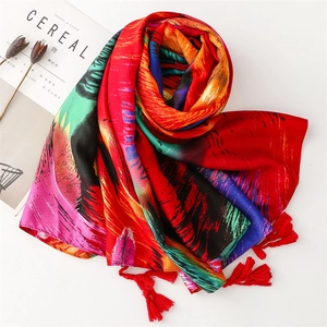 Detail of colorful peacock feather print scarf with red tassels on a white background