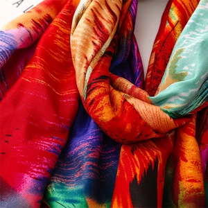 Detail of silk scarf showing vibrant peacock feather patterns and smooth satin texture