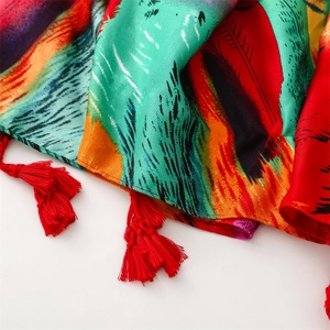 Detail of cotton linen scarf with colorful peacock feather pattern and red tassels
