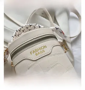 Detail of cream cylinder handbag with faux crocodile texture and floral silk scarf handle