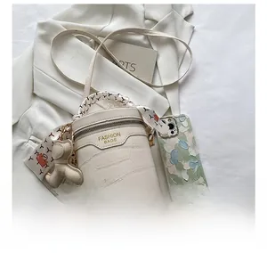 Detail of crocodile embossed barrel bag with silk scarf handle and bear charm