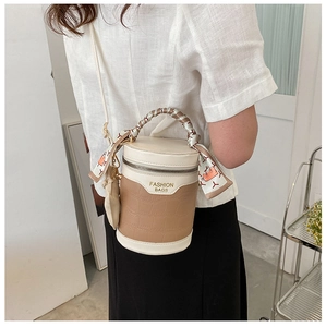 Detail of crocodile embossed cylindrical bag featuring a decorative scarf handle and metal zip