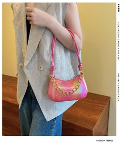 Close-up of a gradient pink and gold Y2K shoulder bag with metallic texture and chain